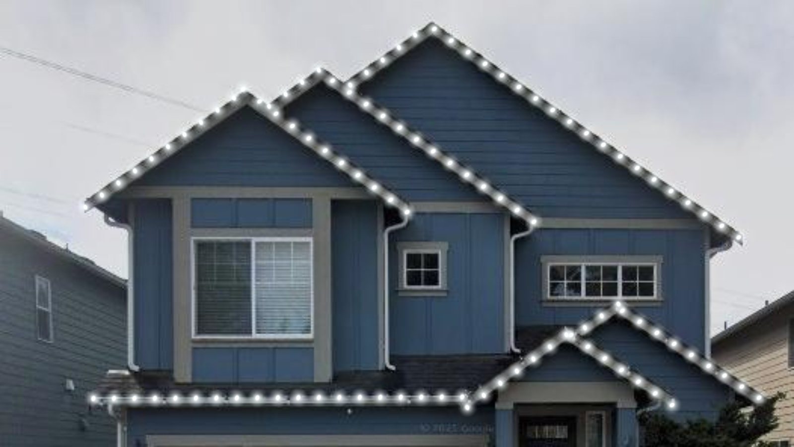 Blue home in August daylight with permanent lighting track along the rooflines