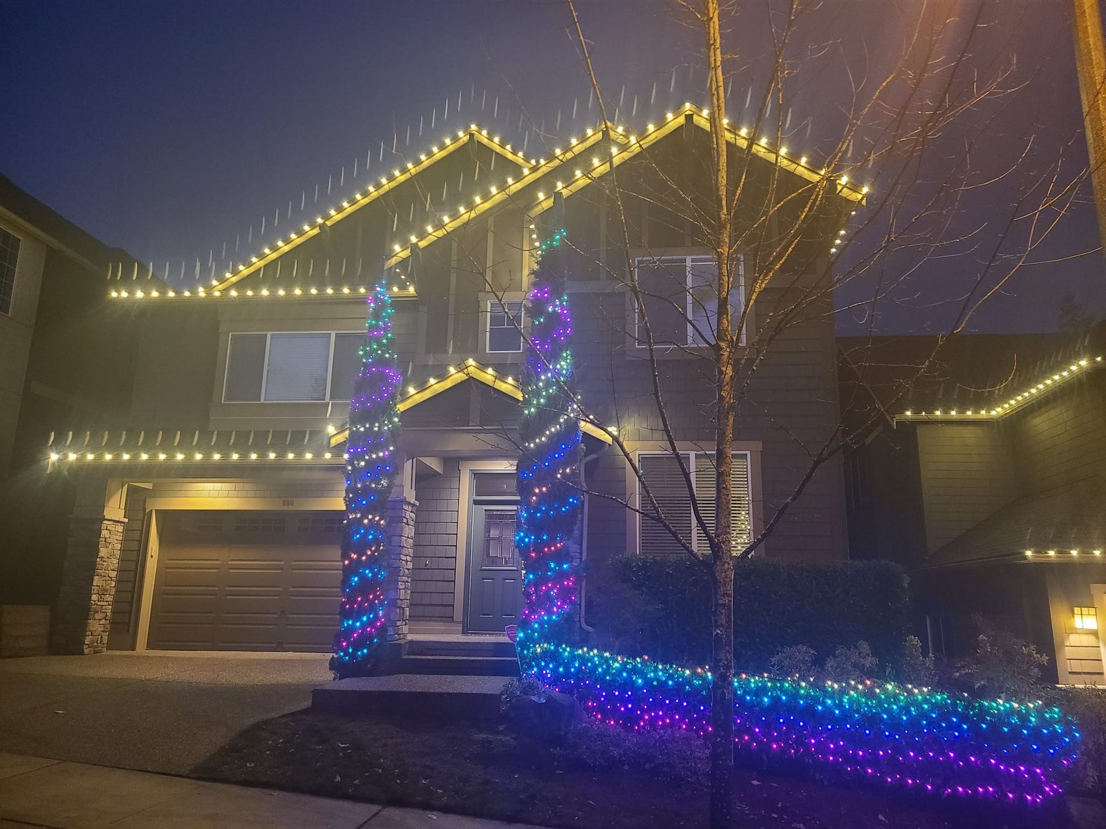 Two-story home at night with warm white roofline and column lighting