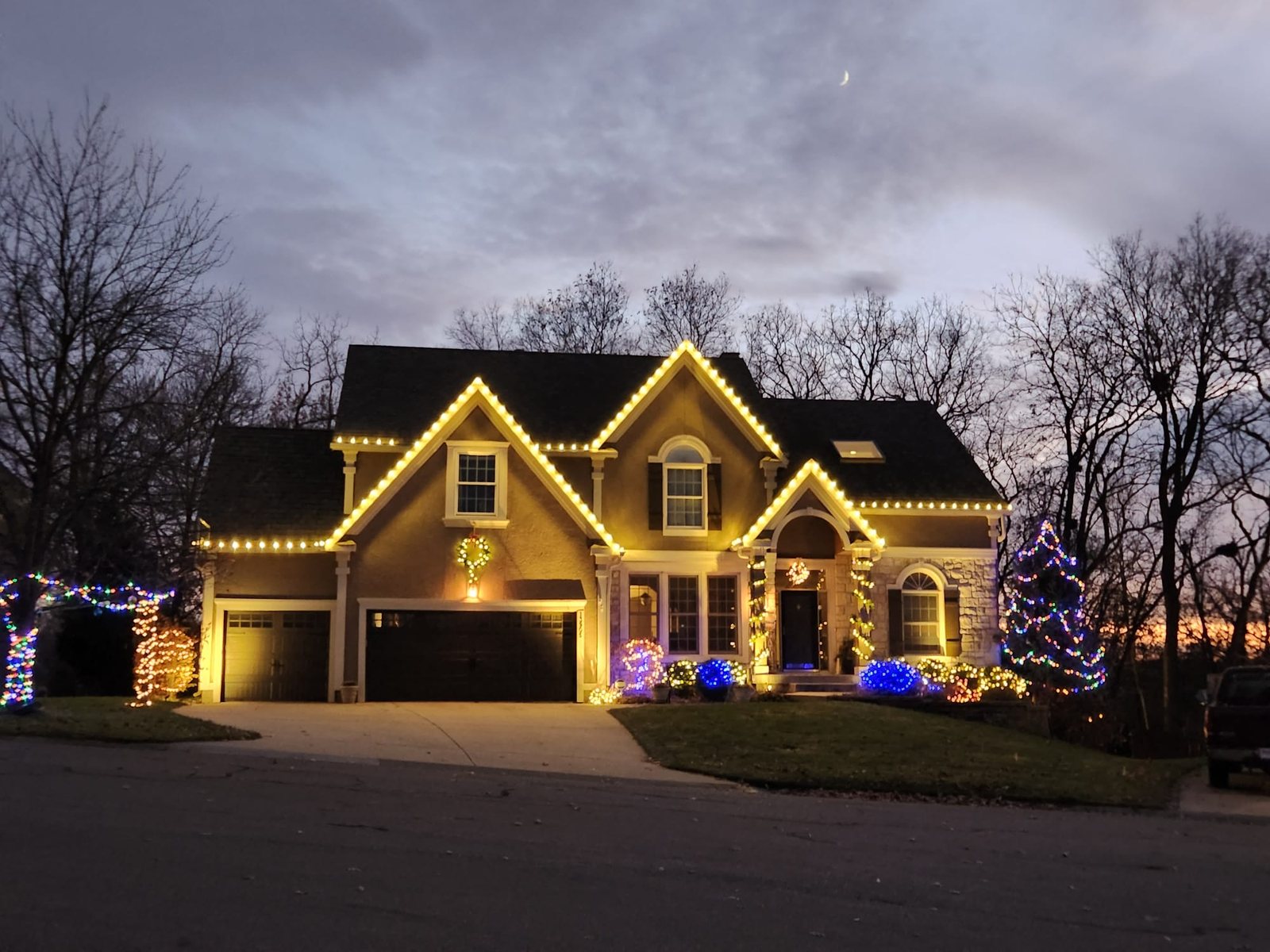 Home at dusk with warm white roofline lighting and a decorated tree