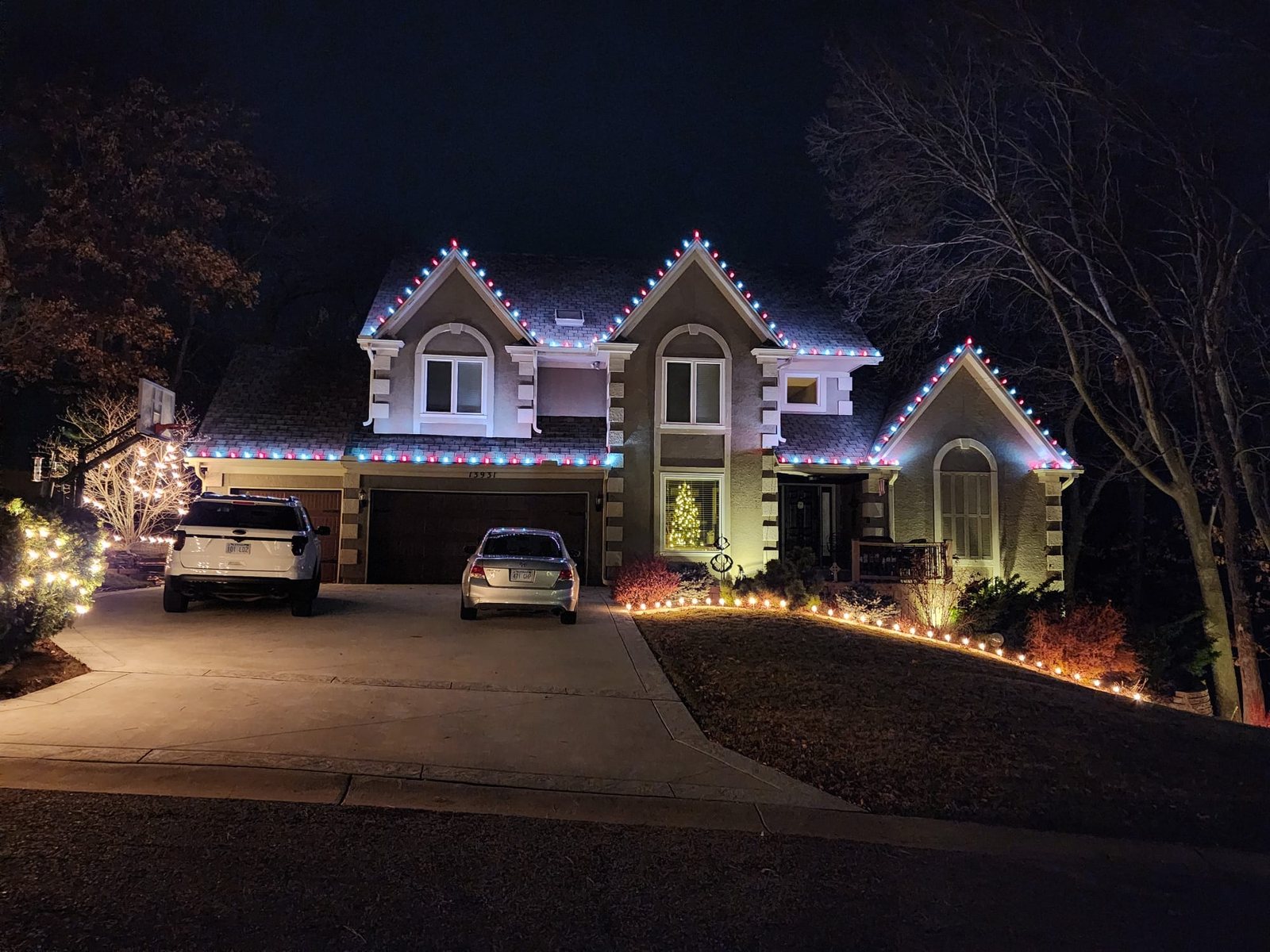 Two-story home at night with warm white roofline lighting