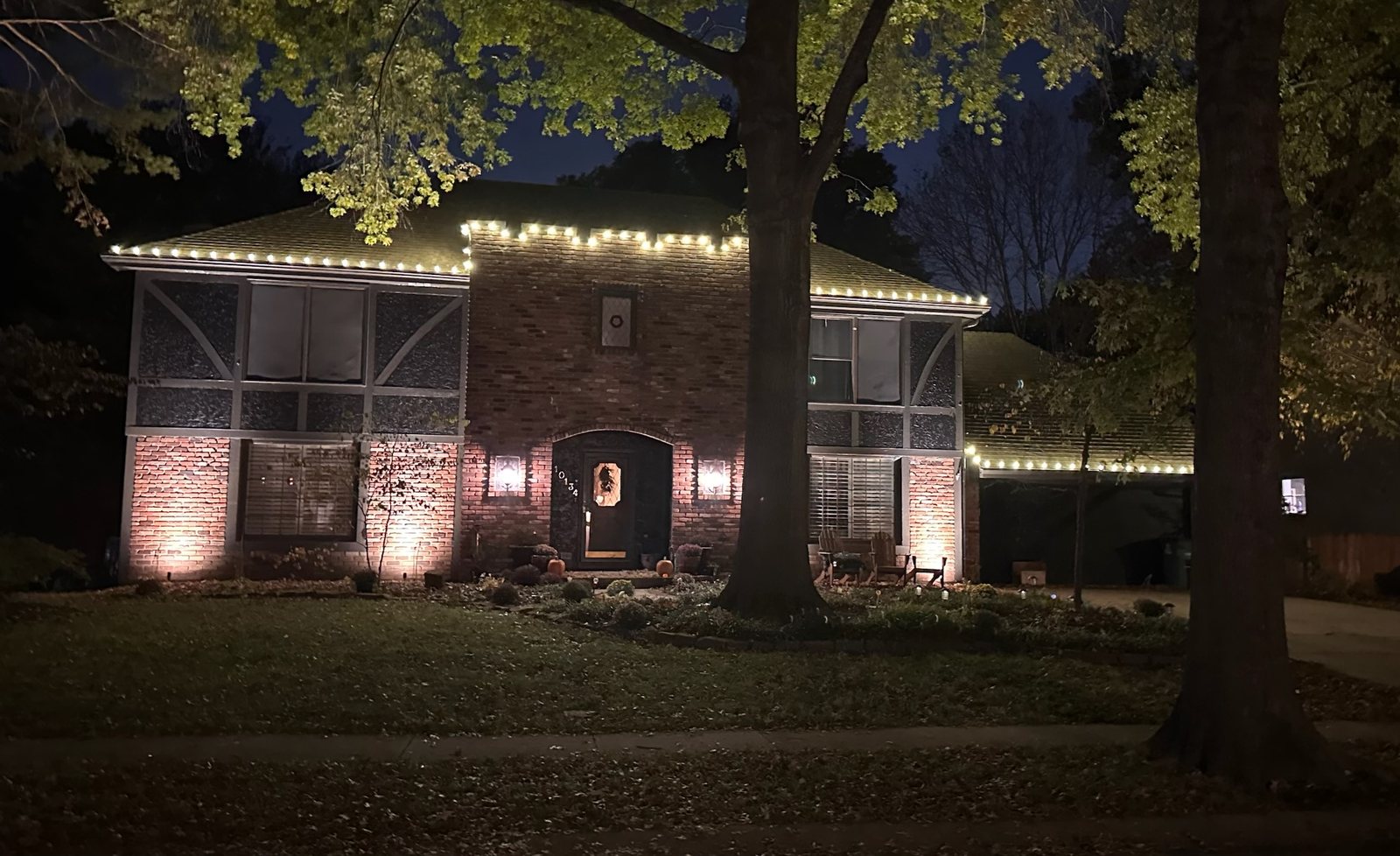 Brick home at night with warm white roofline lighting and uplighting