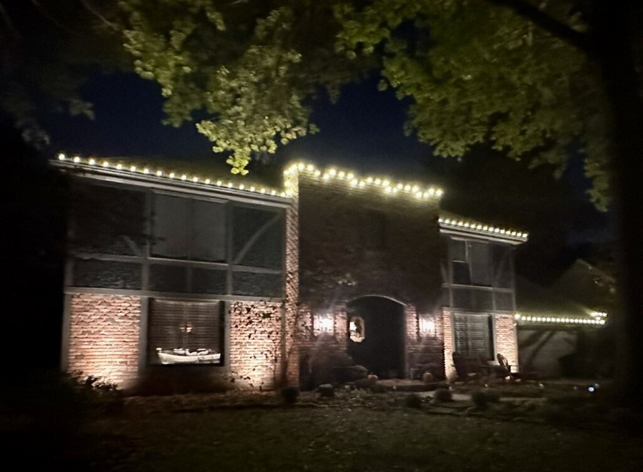 Brick home at night with warm white lighting along the eaves — Newcastle, WA