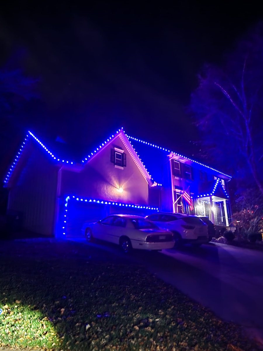 Home lit in deep blue and violet across the rooflines
