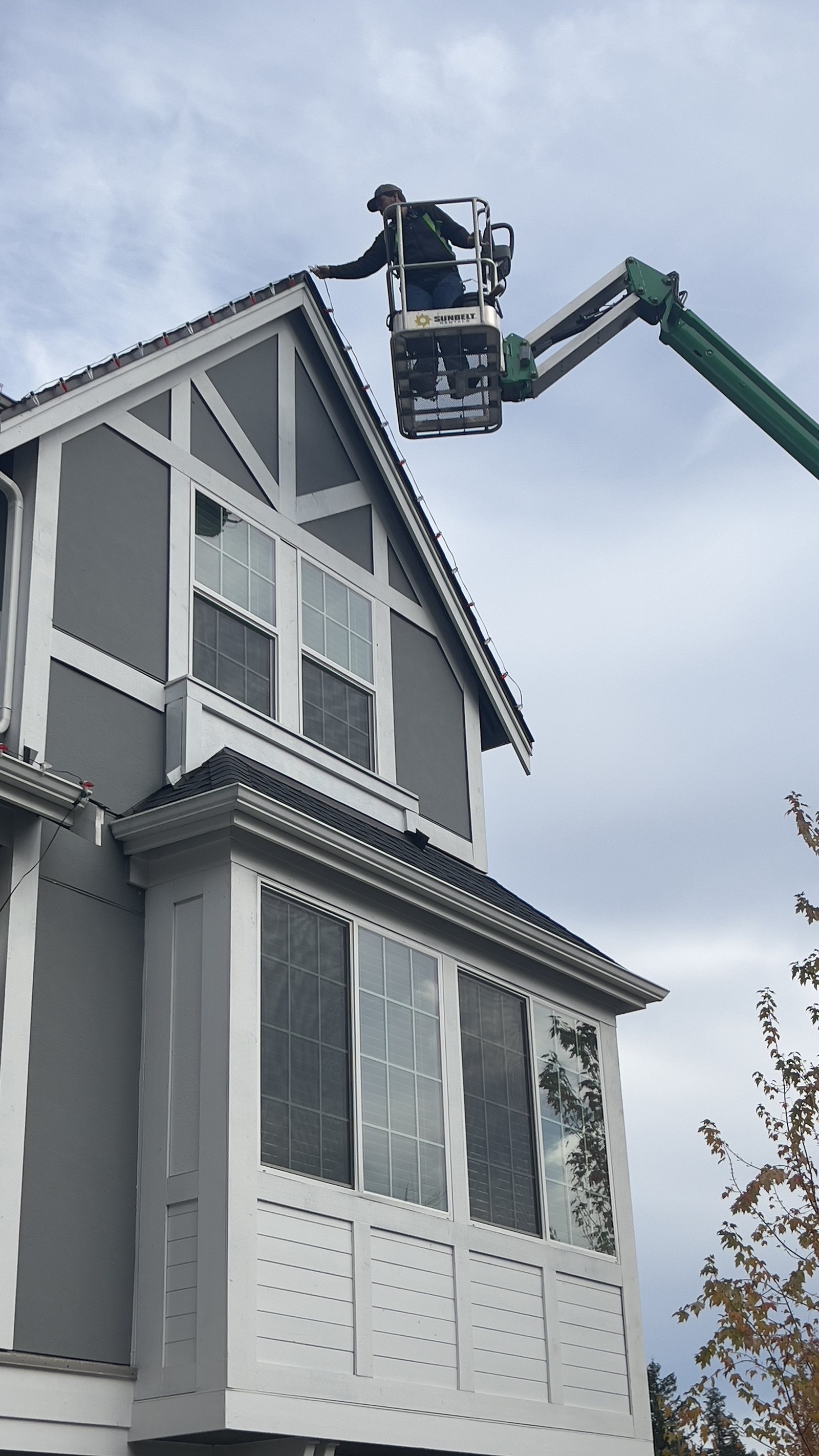 Homefront crew member working from a boom lift on a high gable