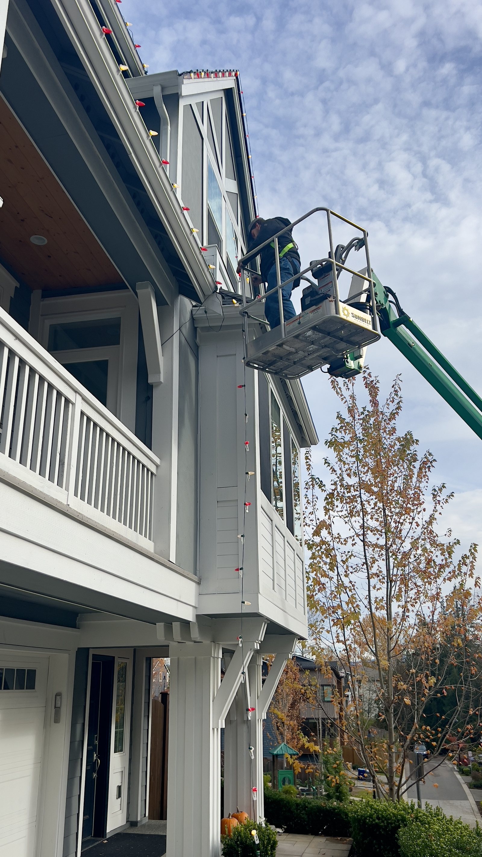 Crew member working from a lift at the upper roofline of a home