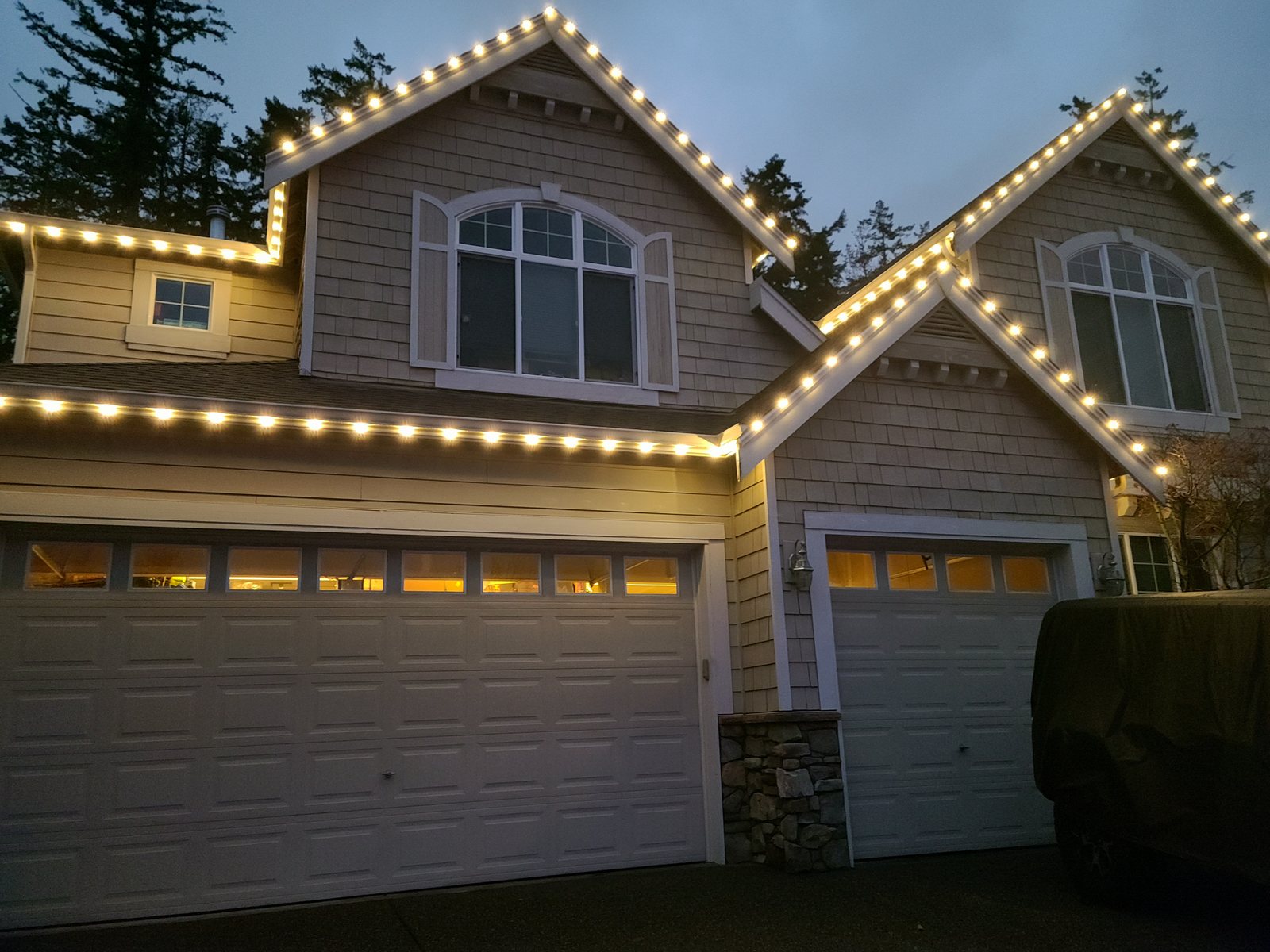 Gabled home at dusk with warm white permanent roofline lighting