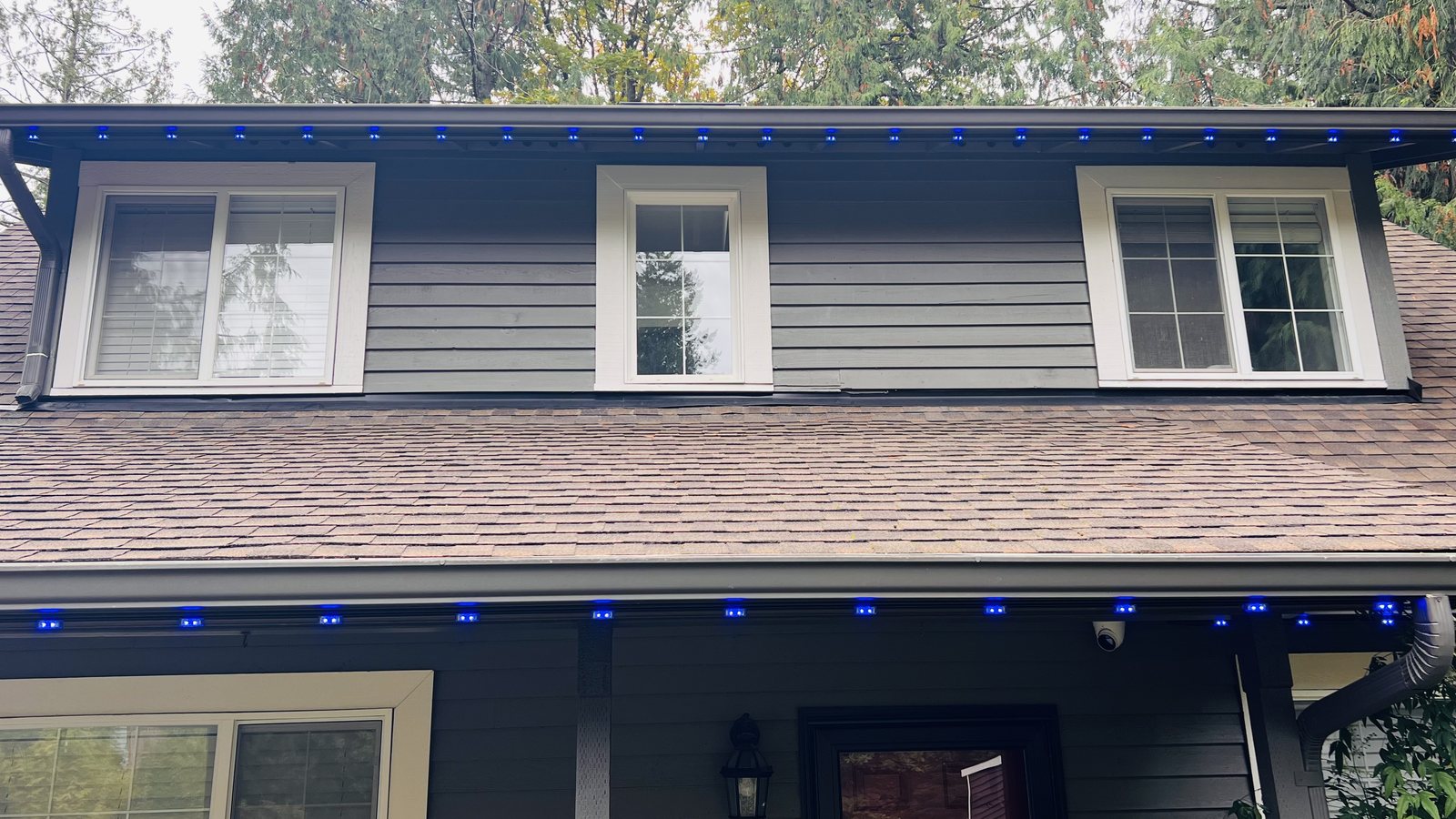Home in daylight with permanent lighting set to blue along the eaves — Kenmore, WA
