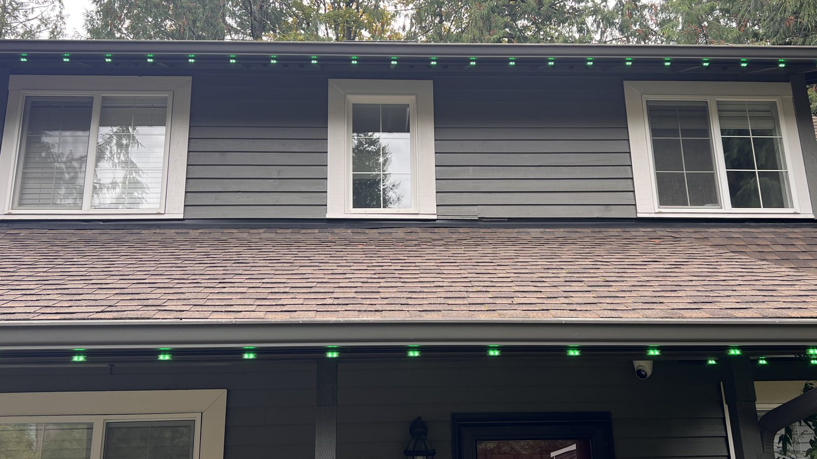 Home in daylight with permanent lighting set to green along the eaves