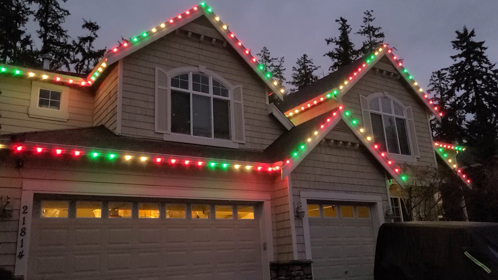 Home at night with permanent roofline lighting in red, green and white
